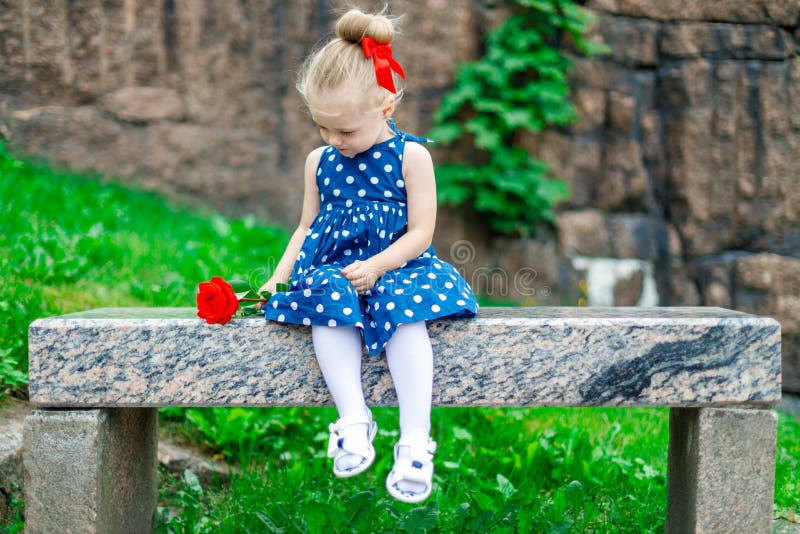 Jovem loira sentada num banco com uma rosa imagem de stock royalty free