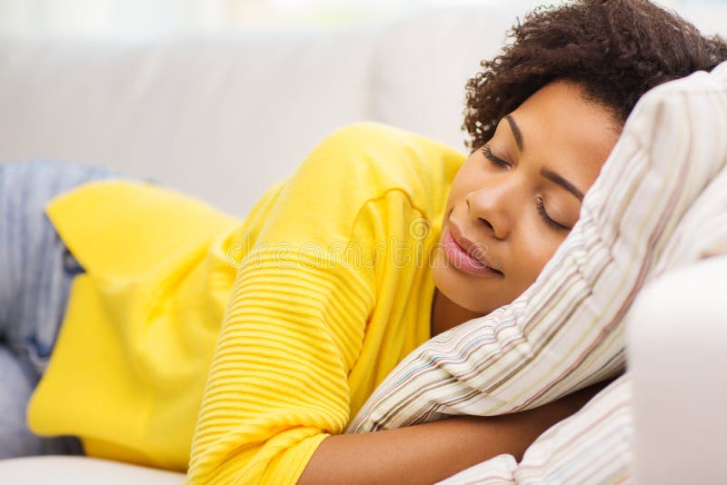 Jovem mulher africana que dorme no sofá em casa