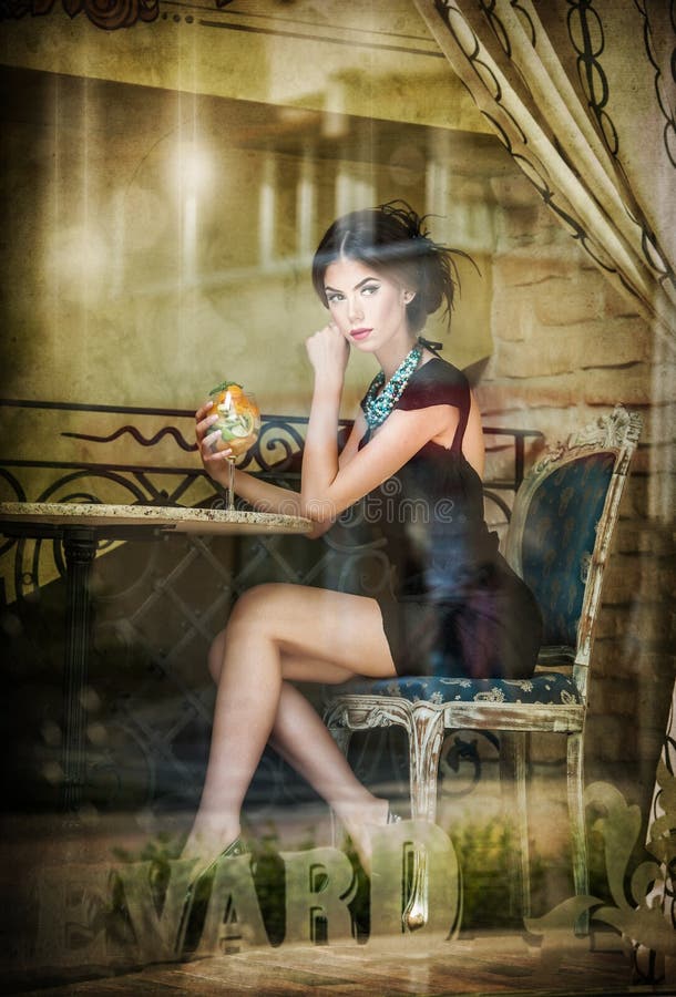 Jovem mulher atrativa elegante no vestido preto que senta-se no restaurante, além da janela Levantamento moreno bonito na janela foto de stock Jovem mulher atrativa elegante no vestido preto que senta-se no restaurante, além da janela Levantamento moreno bonito na janela foto de stock