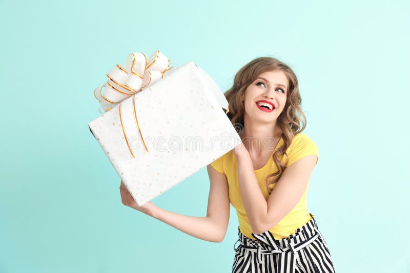 Jovem mulher bonita com a caixa de presente no fundo da cor imagem de stock royalty free Jovem mulher bonita com a caixa de presente no fundo da cor imagem de stock royalty free