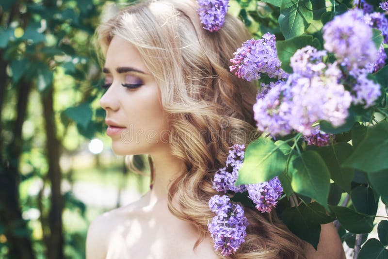 A jovem mulher bonita da forma exterior cercada pelo lilás floresce o verão Arbusto lilás da flor da mola Retrato de uma menina l foto de stock royalty free A jovem mulher bonita da forma exterior cercada pelo lilás floresce o verão Arbusto lilás da flor da mola Retrato de uma menina l foto de stock royalty free
