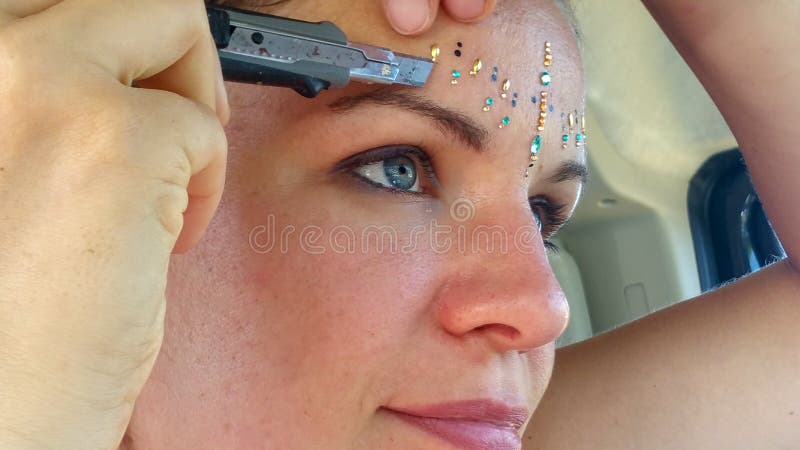 A jovem mulher bonita Dreamlike cola pedras de brilho para o festival com os cristais de rocha do cortador imagens de stock A jovem mulher bonita Dreamlike cola pedras de brilho para o festival com os cristais de rocha do cortador imagens de stock