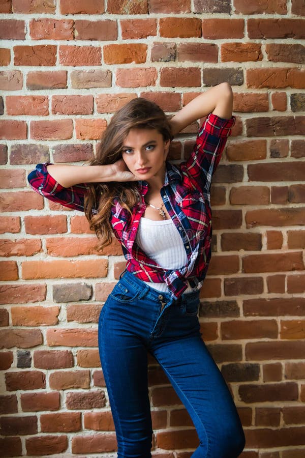 A jovem mulher bonita está perto da parede de tijolo imagens de stock royalty free A jovem mulher bonita está perto da parede de tijolo imagens de stock royalty free