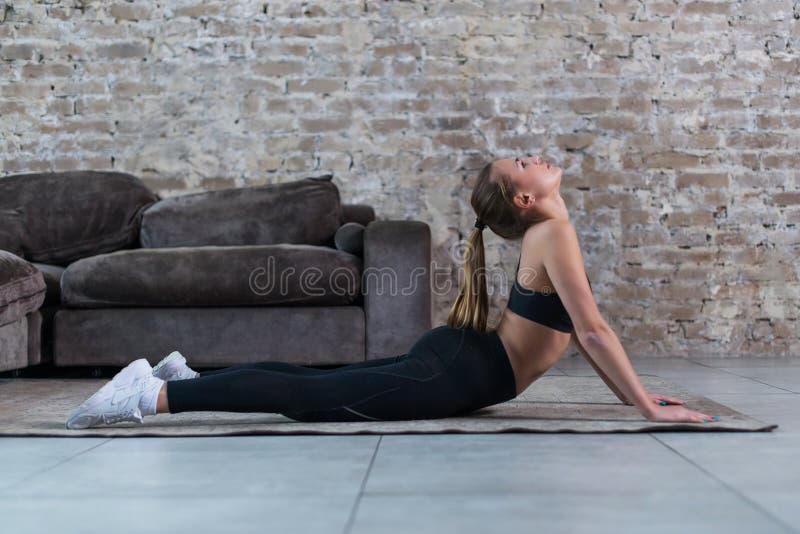 A jovem mulher bonita no aquecimento preto do sportswear muscles antes dá certo, esticando sua espinha, fazendo o arco traseiro foto de stock A jovem mulher bonita no aquecimento preto do sportswear muscles antes dá certo, esticando sua espinha, fazendo o arco traseiro foto de stock