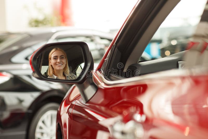 Jovem mulher bonita que compra o carro novo no negócio imagem de stock royalty free Jovem mulher bonita que compra o carro novo no negócio imagem de stock royalty free