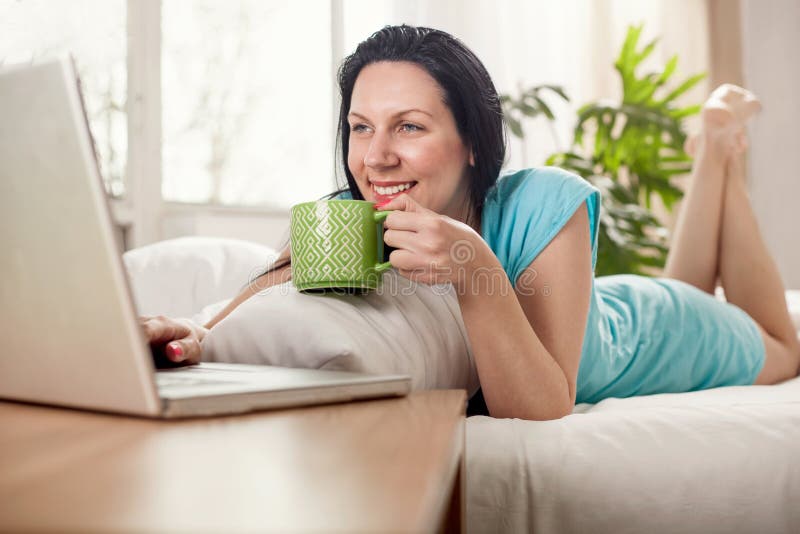 Jovem mulher bonita que encontra-se na cama com xícara de café imagens de stock Jovem mulher bonita que encontra-se na cama com xícara de café imagens de stock