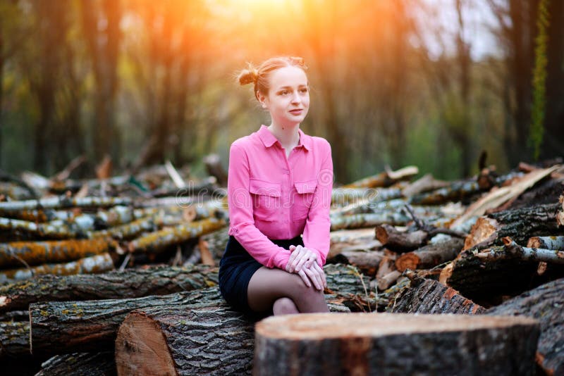 Jovem mulher bonita que senta-se na pilha de troncos de árvore abatidos na floresta fotos de stock royalty free Jovem mulher bonita que senta-se na pilha de troncos de árvore abatidos na floresta fotos de stock royalty free