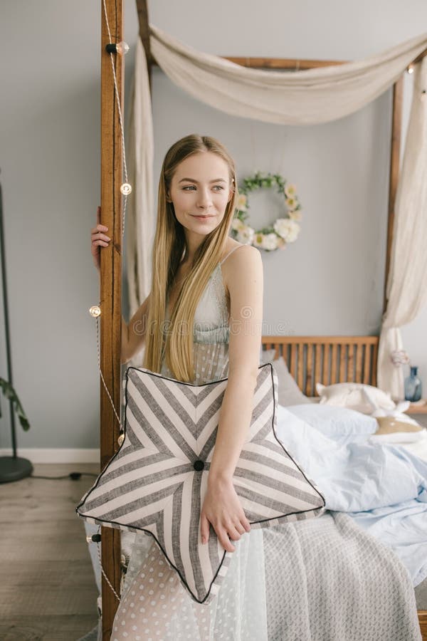 A jovem mulher bonita que veste pijamas na cama em casa está guardando um descanso imagem de stock A jovem mulher bonita que veste pijamas na cama em casa está guardando um descanso imagem de stock