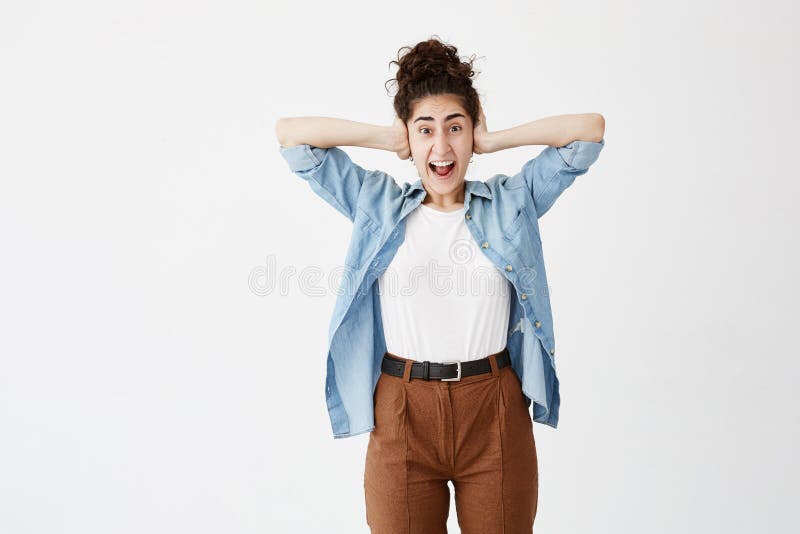 A jovem mulher com cabelo escuro no bolo que grita no terror com mãos em sua cabeça, mouth largamente a vista aberta no pânico no imagens de stock A jovem mulher com cabelo escuro no bolo que grita no terror com mãos em sua cabeça, mouth largamente a vista aberta no pânico no imagens de stock