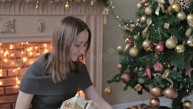 Jovem mulher com os presentes na frente da árvore de Natal