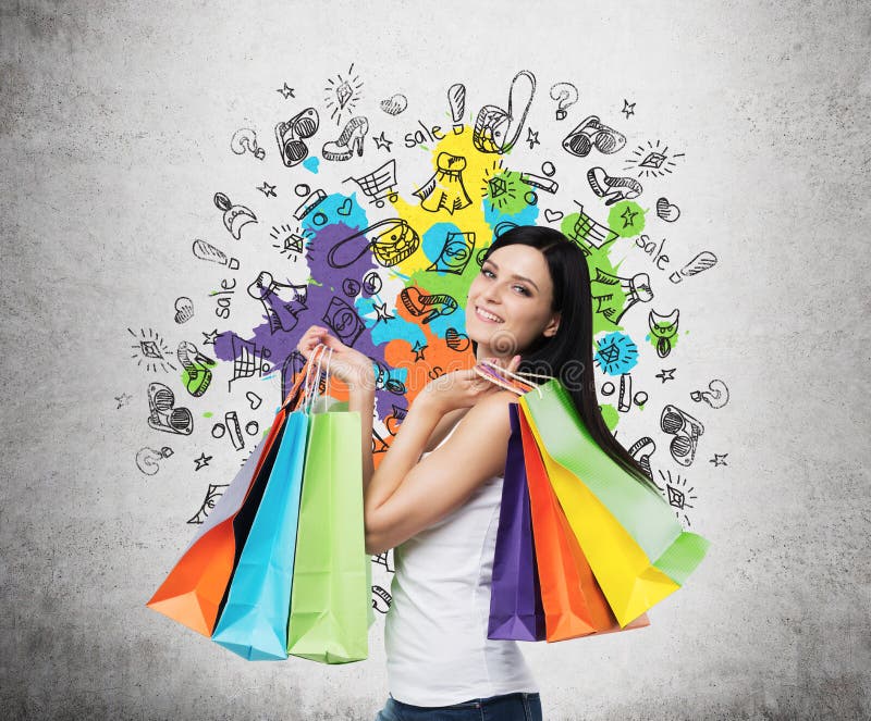 Jovem mulher de sorriso bonita com os sacos de compras coloridos das lojas extravagantes imagem de stock royalty free Jovem mulher de sorriso bonita com os sacos de compras coloridos das lojas extravagantes imagem de stock royalty free