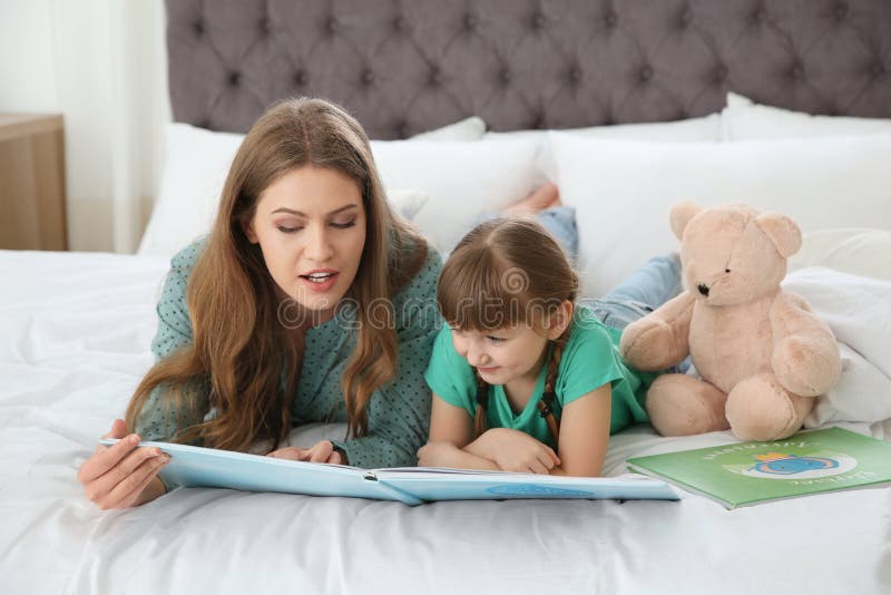 Jovem mulher e seu livro de leitura da filha r imagem de stock Jovem mulher e seu livro de leitura da filha r imagem de stock