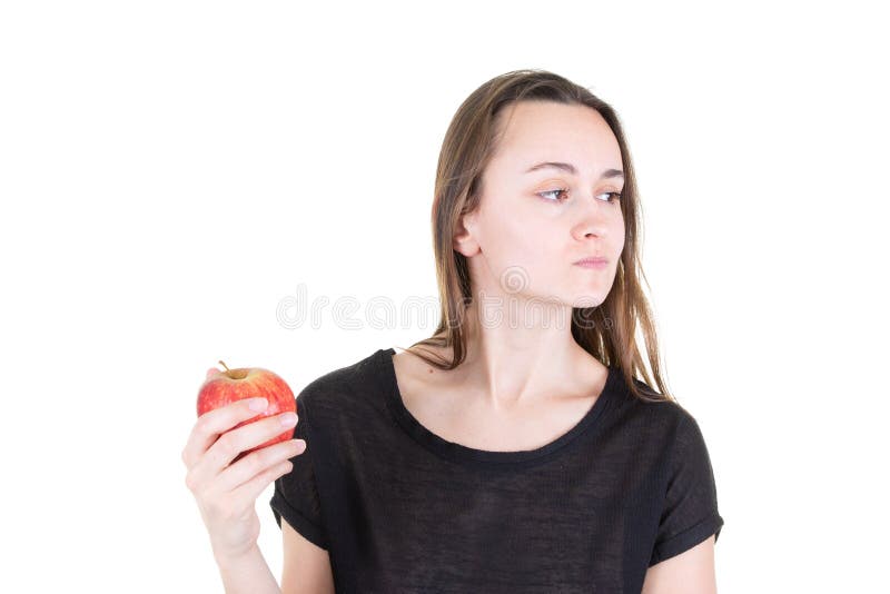 Jovem mulher enojado que guarda a maçã vermelha e que olha de lado na dieta saudável do vegetariano do começo fotos de stock royalty free Jovem mulher enojado que guarda a maçã vermelha e que olha de lado na dieta saudável do vegetariano do começo fotos de stock royalty free
