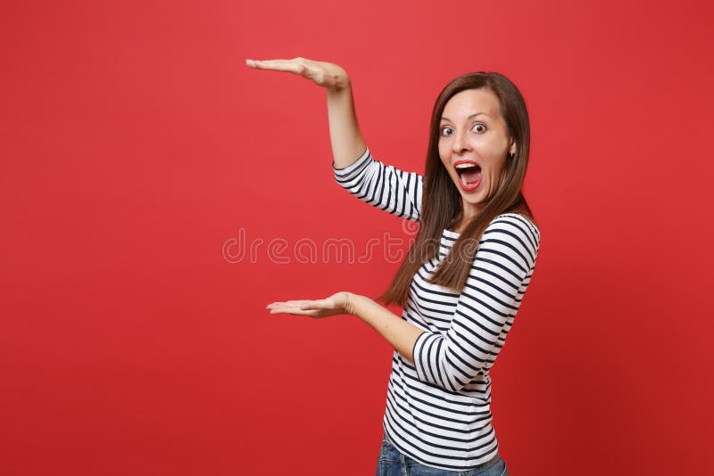 A jovem mulher entusiasmado que gesticula demonstrando o tamanho com espaço da cópia, mantendo a boca largamente aberta, olhando imagem de stock royalty free A jovem mulher entusiasmado que gesticula demonstrando o tamanho com espaço da cópia, mantendo a boca largamente aberta, olhando imagem de stock royalty free