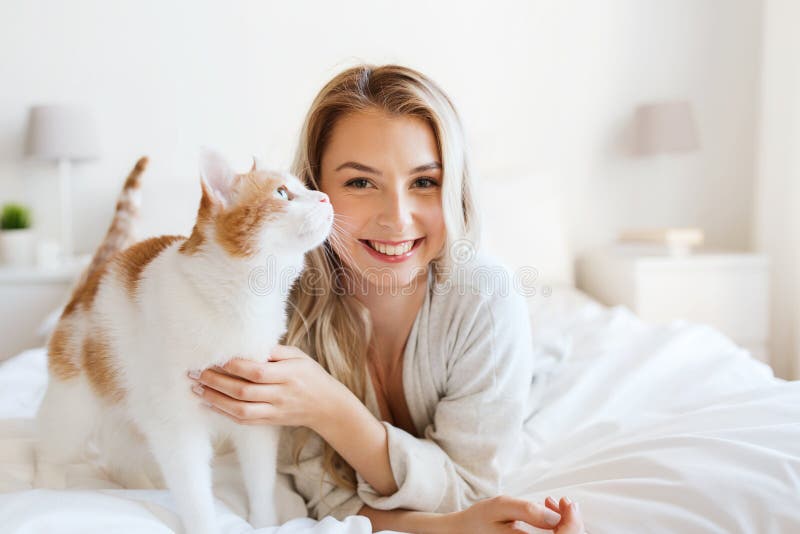 Jovem mulher feliz com o gato na cama em casa imagens de stock royalty free Jovem mulher feliz com o gato na cama em casa imagens de stock royalty free