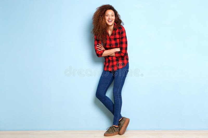 Jovem mulher feliz do corpo completo que inclina-se contra a parede azul fotos de stock Jovem mulher feliz do corpo completo que inclina-se contra a parede azul fotos de stock