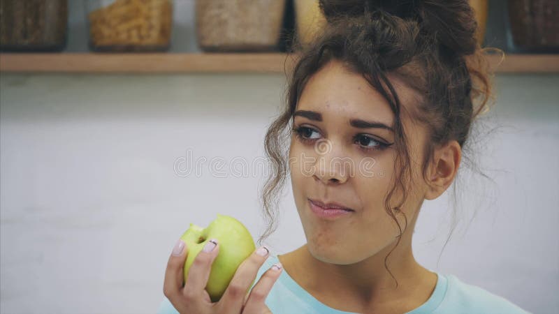 Jovem mulher feliz que come a maçã na cozinha Dieta Conceito de dieta Alimento saudável Afrouxar pesa