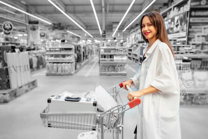Jovem mulher feliz que empurra o trole no supermercado fotos de stock Jovem mulher feliz que empurra o trole no supermercado fotos de stock