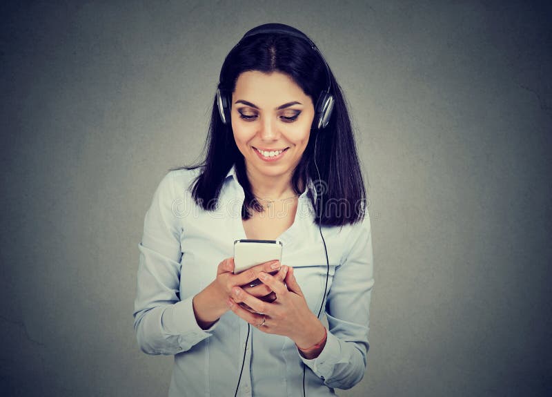 Jovem mulher feliz que escuta a música no telefone celular imagem de stock royalty free Jovem mulher feliz que escuta a música no telefone celular imagem de stock royalty free