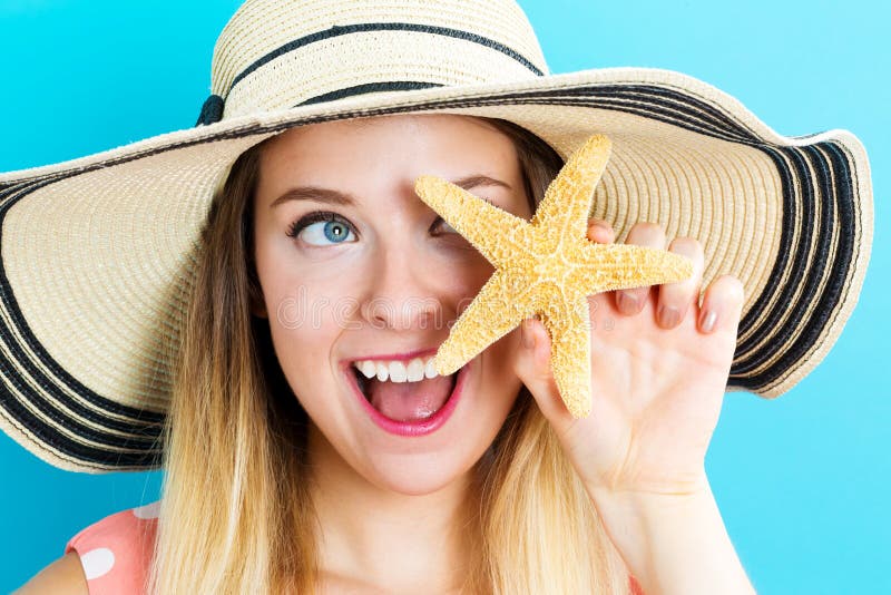 Jovem mulher feliz que guarda uma estrela do mar imagem de stock Jovem mulher feliz que guarda uma estrela do mar imagem de stock