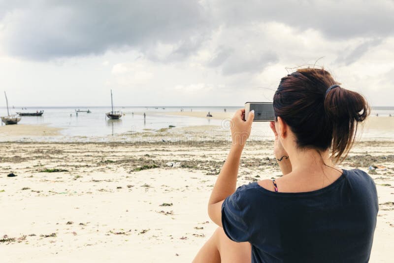 A jovem mulher fotografa um oceano do telefone celular fotos de stock royalty free A jovem mulher fotografa um oceano do telefone celular fotos de stock royalty free