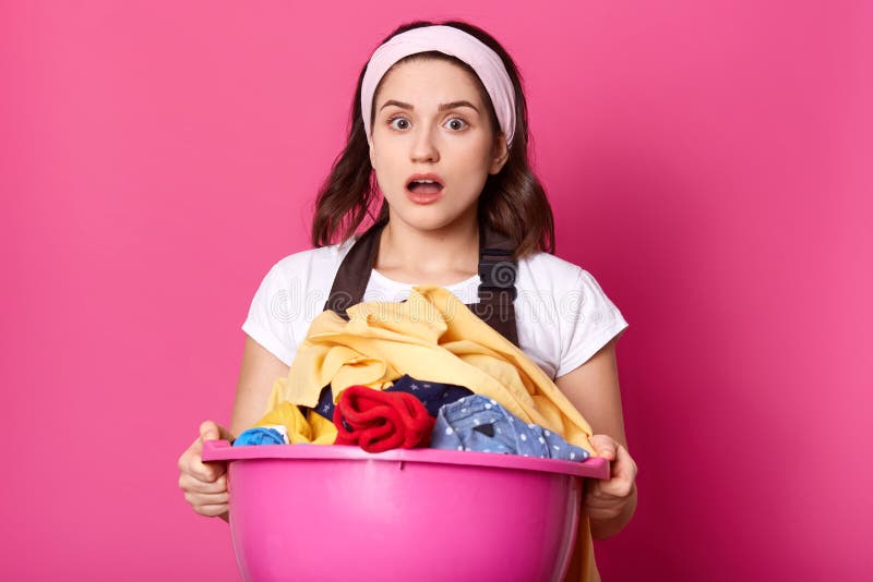 A jovem mulher guarda a bacia completamente do linho limpo, dona de casa parece cansado após ter feito a lavanderia, trabalhos so foto de stock A jovem mulher guarda a bacia completamente do linho limpo, dona de casa parece cansado após ter feito a lavanderia, trabalhos so foto de stock