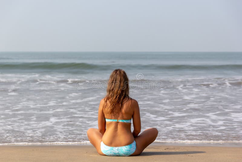 A jovem mulher medita o assento no oceano imagem de stock A jovem mulher medita o assento no oceano imagem de stock