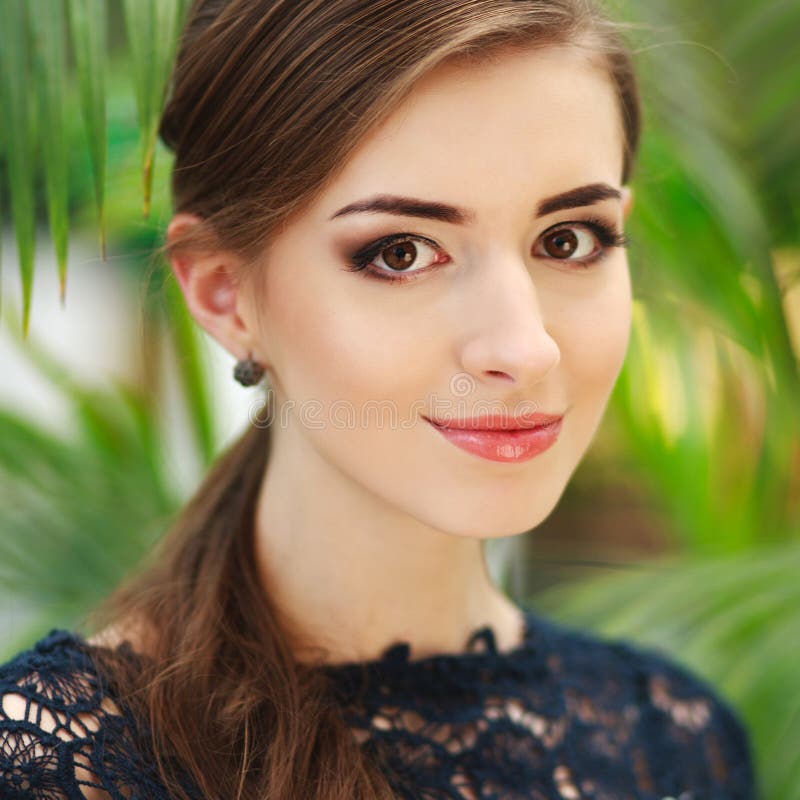 Jovem mulher moreno agradável, no fundo da folha do verde do verão imagens de stock royalty free Jovem mulher moreno agradável, no fundo da folha do verde do verão imagens de stock royalty free