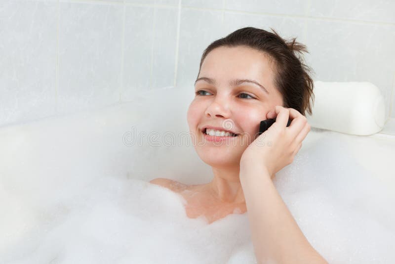 Jovem mulher na banheira que fala no móbil imagens de stock royalty free Jovem mulher na banheira que fala no móbil imagens de stock royalty free