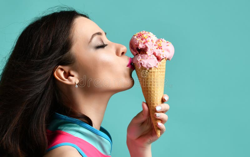 A jovem mulher no chapéu cor-de-rosa come a sobremesa do gelado da morango no cone do waffle na luz moderna - azul fotos de stock royalty free A jovem mulher no chapéu cor-de-rosa come a sobremesa do gelado da morango no cone do waffle na luz moderna - azul fotos de stock royalty free