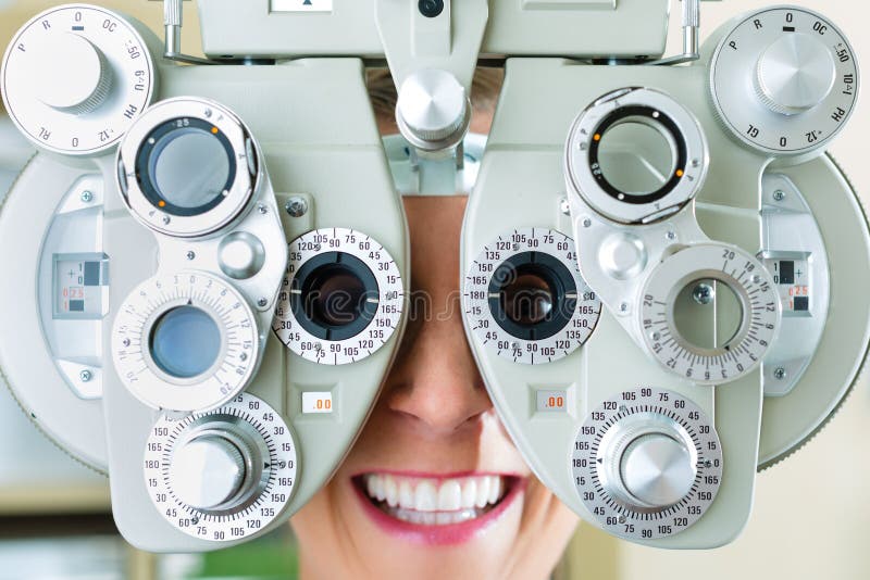 Young woman at phoropter at optician or ophthalmologist for eye test, she is near-sighted or long-sighted. Young woman at phoropter at optician or ophthalmologist for eye test, she is near-sighted or long-sighted