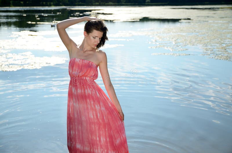 Jovem mulher no vestido vermelho no lago fotos de stock Jovem mulher no vestido vermelho no lago fotos de stock