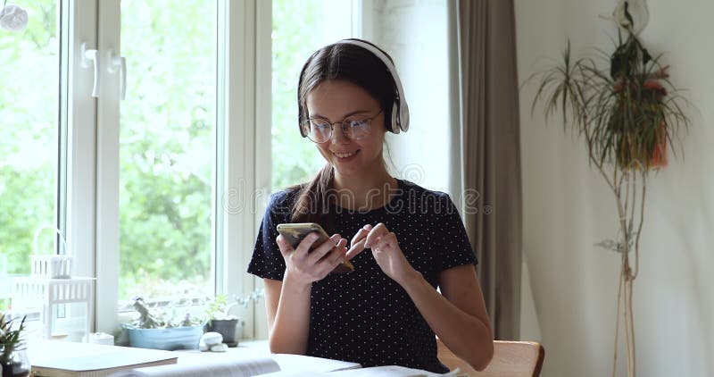 Jovem mulher nos fones de ouvido usando sms de celular para amigo