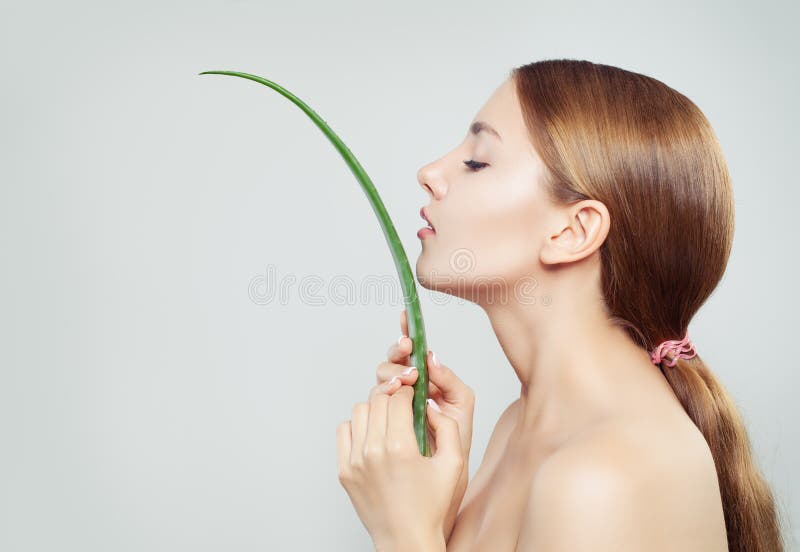 Perfect young woman with healthy hair and clear skin holding green aloe vera leaf, female profile. Perfect young woman with healthy hair and clear skin holding green aloe vera leaf, female profile