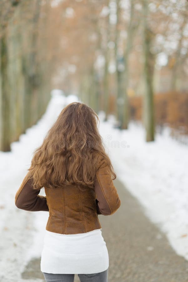 Jovem mulher que anda no parque do inverno. vista traseira
