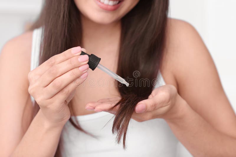 Jovem mulher que aplica o óleo em seu cabelo, imagens de stock royalty free Jovem mulher que aplica o óleo em seu cabelo, imagens de stock royalty free