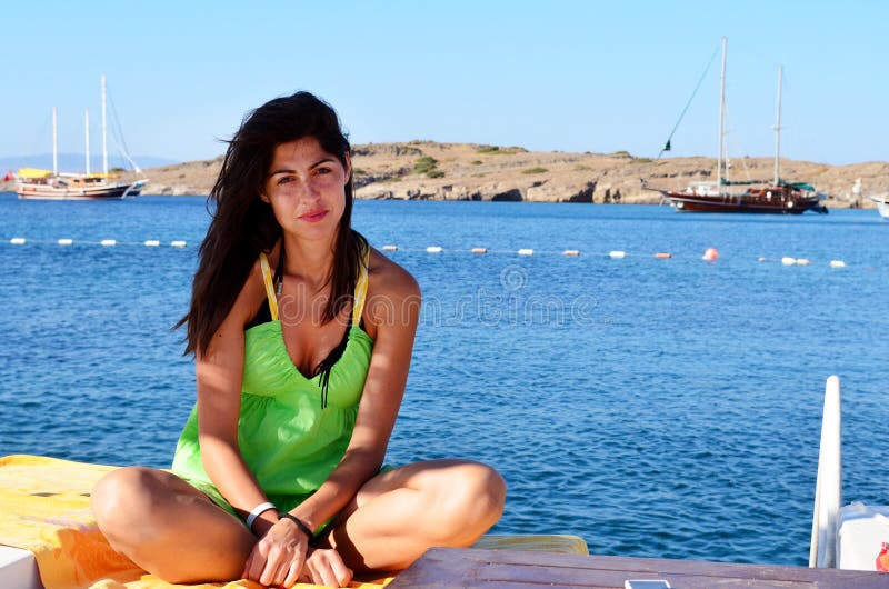 Jovem mulher que aprecia as férias de verão que sentam no oon sunbed a praia imagens de stock royalty free Jovem mulher que aprecia as férias de verão que sentam no oon sunbed a praia imagens de stock royalty free