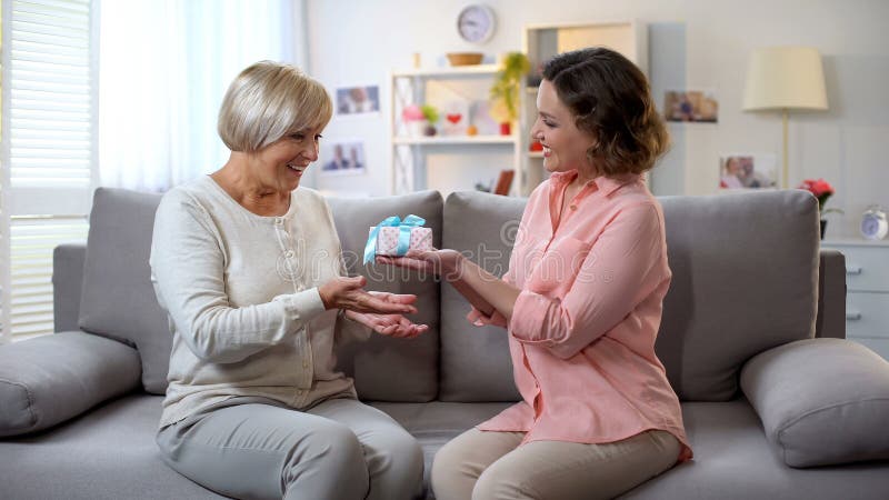 Jovem mulher que apresenta a caixa de presente para serir de mãe, cuidado da família, celebração do aniversário imagem de stock Jovem mulher que apresenta a caixa de presente para serir de mãe, cuidado da família, celebração do aniversário imagem de stock