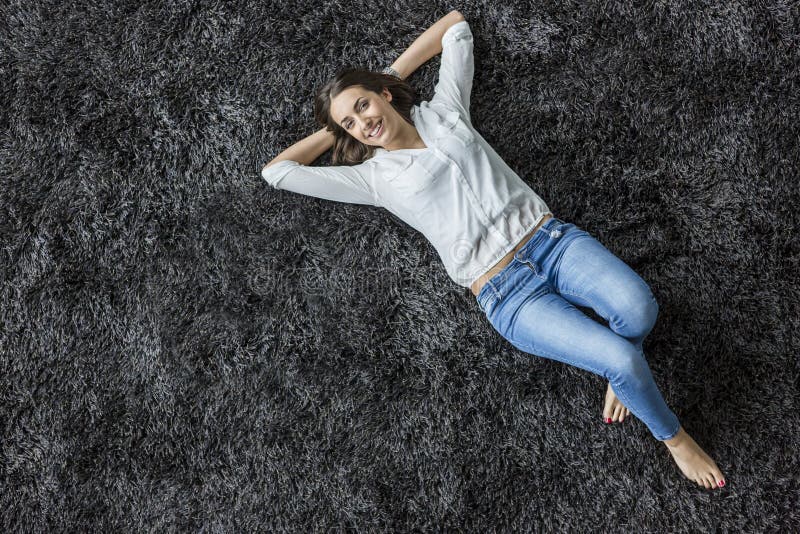Jovem mulher que coloca no tapete imagem de stock royalty free Jovem mulher que coloca no tapete imagem de stock royalty free