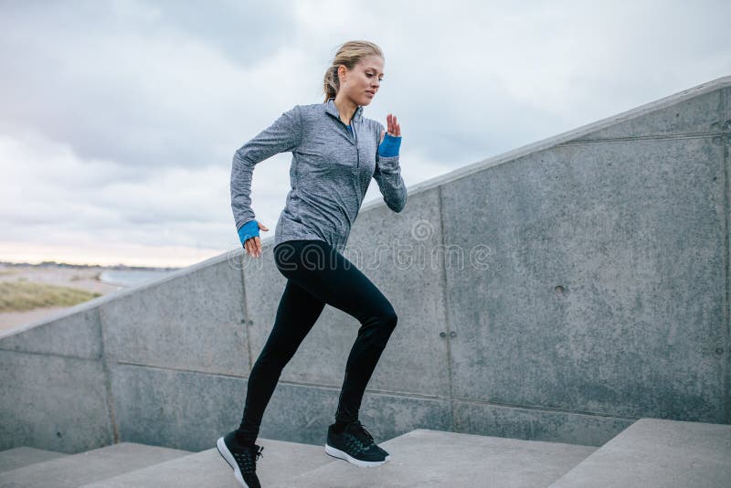 Jovem mulher a correr sozinha pelas escadas imagem de stock