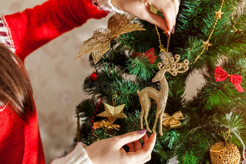 Jovem mulher que decora a árvore de Natal em casa, vestindo a camiseta do inverno Preparação ao ano novo Close up da rena fotos de stock Jovem mulher que decora a árvore de Natal em casa, vestindo a camiseta do inverno Preparação ao ano novo Close up da rena fotos de stock