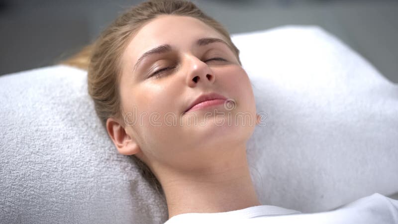 Jovem mulher que encontra-se para baixo e que relaxa no salão de beleza do cosmetologist, cuidados com a pele foto de stock Jovem mulher que encontra-se para baixo e que relaxa no salão de beleza do cosmetologist, cuidados com a pele foto de stock