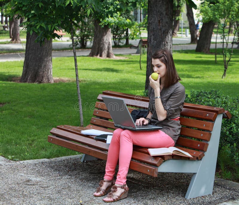 Jovem mulher que estuda em um parque foto de stock royalty free