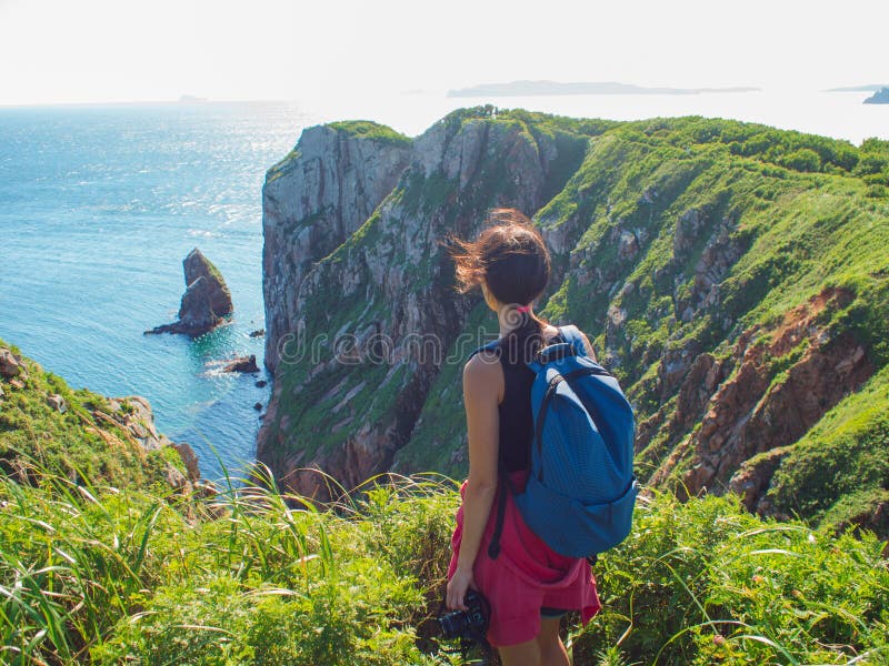 Jovem mulher que está apenas em um penhasco rochoso, fotógrafo do turista da menina no fundo de animais selvagens bonitos fotos de stock Jovem mulher que está apenas em um penhasco rochoso, fotógrafo do turista da menina no fundo de animais selvagens bonitos fotos de stock