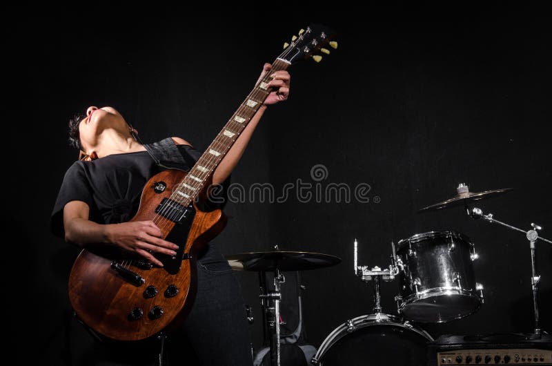 Jovem mulher que joga a guitarra durante fotografia de stock Jovem mulher que joga a guitarra durante fotografia de stock