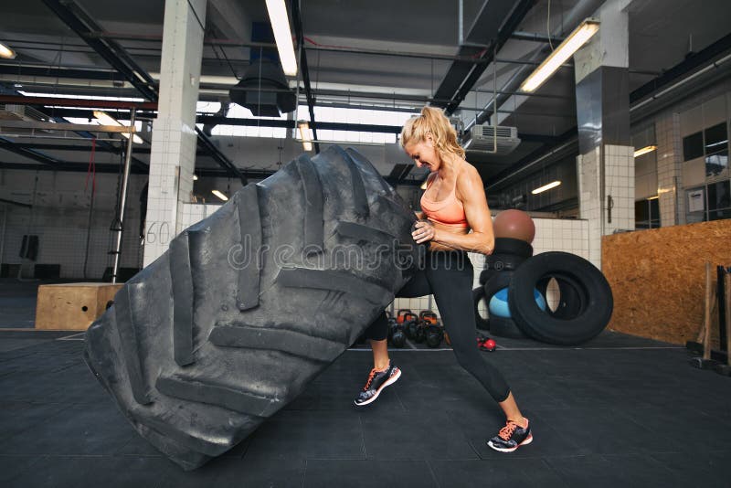Jovem a virar pneu no ginásio imagens de stock
