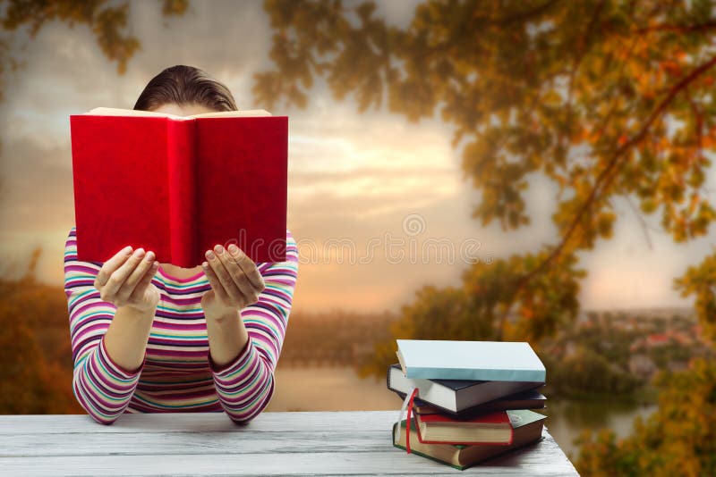 Jovem mulher que lê um livro e que cobre sua cara imagem de stock Jovem mulher que lê um livro e que cobre sua cara imagem de stock