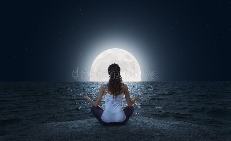 Jovem mulher que medita sobre a praia na Lua cheia