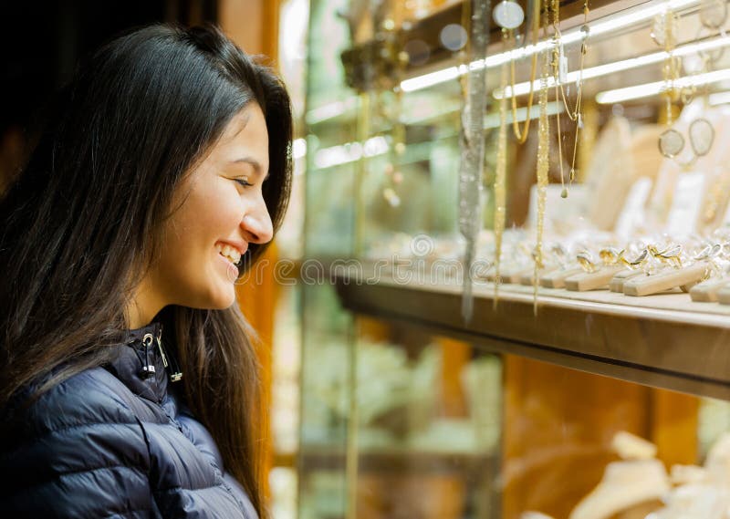Jovem mulher que olha a mostra de uma joia exterior imagem de stock Jovem mulher que olha a mostra de uma joia exterior imagem de stock