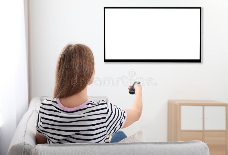 Jovem mulher que olha a tevê no sofá em casa fotografia de stock Jovem mulher que olha a tevê no sofá em casa fotografia de stock